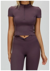 Dettaglio del crop top yoga viola scuro con collo alto e mezza cerniera sulla parte anteriore