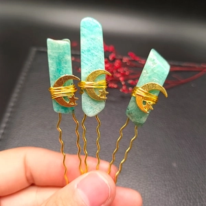 Detailed view of handmade gold hairpins with natural green crystals and celestial charms