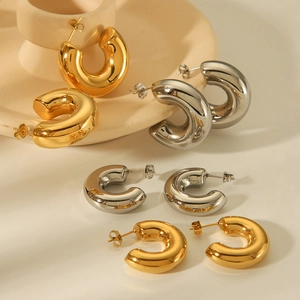Polished gold and silver stainless steel C-shape earrings on ceramic display
