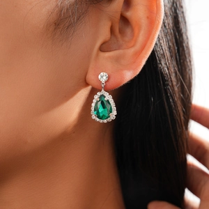 Close-up of elegant green pear-shaped drop earrings with halo crystals and silver finish