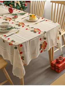 Detail of Christmas lace tablecloth featuring holly and bell embroidery on wooden table