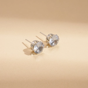 Luxury silver stud earrings with 6-prong round zircon stones on beige background