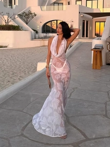 Deep V-neck white sheer halter beach dress with tropical leaf print in sunset lighting