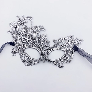 Close-up of silver lace masquerade mask with intricate embroidery and black ribbons