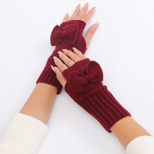 Macro detail of wine red knitted fingerless gloves with bow decoration and ribbed cuffs