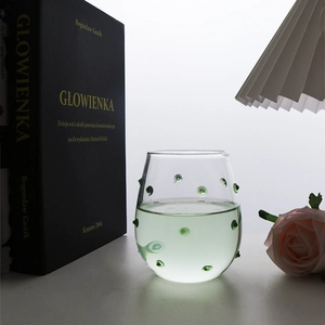 Detail of creative wavy glass cup featuring vibrant green 3D polka dots and rounded rim