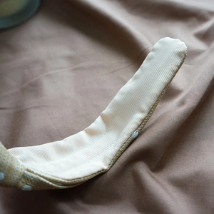 Detailed close-up of beige raffia woven headband featuring white stitched inner lining