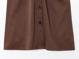Close-up of brown fabric texture with black round buttons and precise stitching details