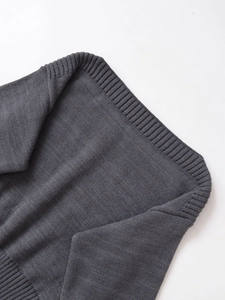 Dettaglio macro di un maglione grigio scuro che mostra la trama a coste e le cuciture