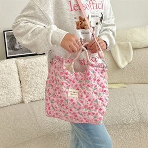 Détail du sac à main matelassé à fleurs roses avec bandoulière et étiquette tissée