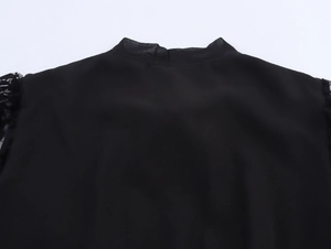 Dettaglio dello scollo in mesh nero e dell'inserto in pizzo sul vestito elegante