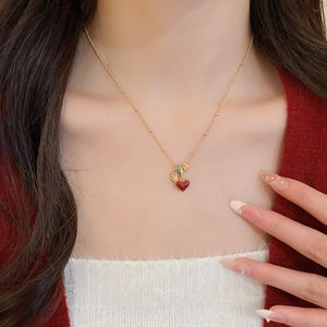 Detail of red heart pendant with 18k gold plating on a delicate chain worn by a model