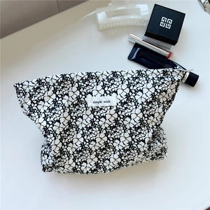 Detail view of floral cotton toiletry bag with zipper and simple wish label on marble