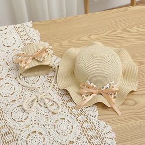 Détail d'un chapeau de paille et sac assorti avec nœud floral sur dentelle