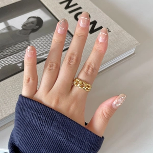 Close-up of a gold Cuban chain ring on a woman's hand with manicured nails