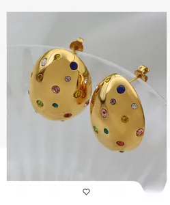 Detail of oval gold earrings with colorful rhinestones and hammered texture