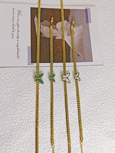Detail of four butterfly pendant necklaces with green stripe and white shell in 18k gold finish
