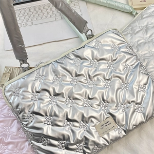 Close-up of quilted laptop sleeve with bow texture and brand label in silver and pink