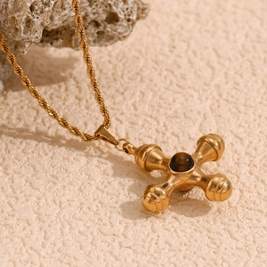 Detail of 18K gold-plated rudder pendant with dark gemstone on a twisted chain
