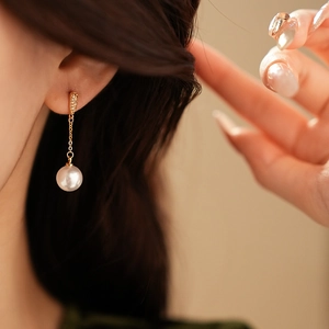 Detail of gold-plated drop earring featuring a white round pearl and micro-inlaid zircons