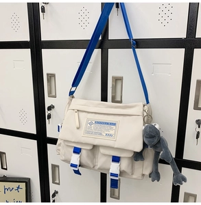 Detail of minimalist beige messenger bag with blue adjustable straps on a locker