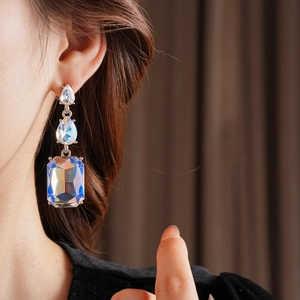 Close-up of elegant drop earrings featuring iridescent teardrop and rectangular crystals