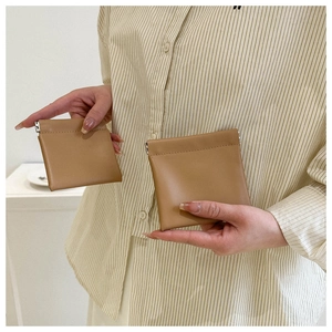 Close-up of brown leather squeeze coin purses with metallic spring closure held by a model