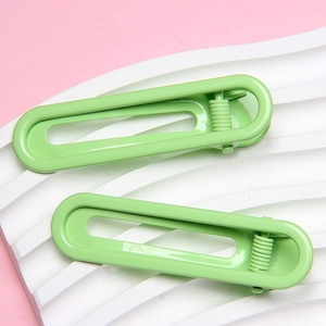 Pair of 6cm lime green U-shaped glossy metal hair clips on a pink and white background