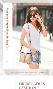Detail of beige bucket bag with metal ring tassel and wide lettered shoulder strap