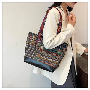 Close-up of ethnic tote bag with geometric wave patterns and black leather bottom panel