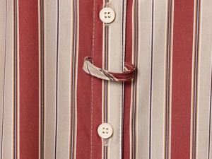 Détail d'un tissu rayé rouge et beige avec des boutons blancs et une boucle en tissu