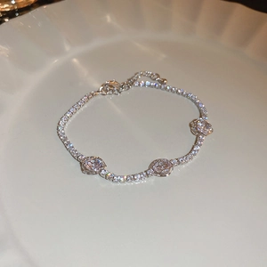 Macro shot of silver camellia bracelet with sparkling zircon stones on a white ceramic plate