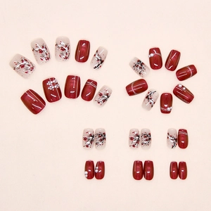 Detail view of red cat-eye press-on nails with plum blossom art and pearl accents