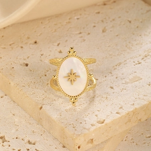 Detail of gold oval mother-of-pearl ring with star pattern on stone slab background