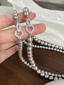 Close-up of a grey pearl necklace with sparkling zircon-encrusted ring clasps detail