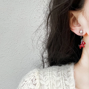 Star and red horse drop earrings for women worn by a model against a grey background