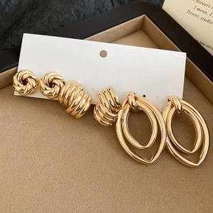 Three pairs of golden earrings set including knot studs, twisted hoops and oval pendants