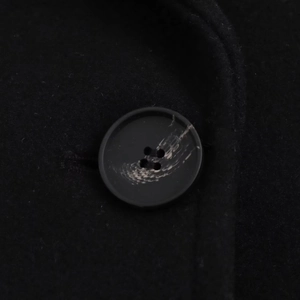 Macro detail of the elegant four-hole black resin button on a warm wool coat fabric