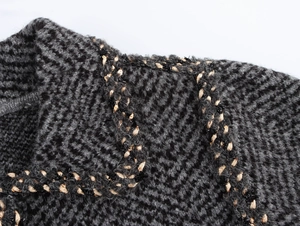 Close-up of dark grey knit fabric texture with beige braided trim detail on jacket