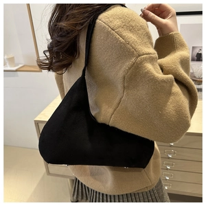 Classic black suede underarm bag for women worn over a sweater in a cozy indoor setting