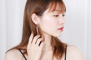 Detailed view of silver long chain earrings featuring LOVE letter charms worn by a model