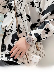 Close-up of sparkling diamond-encrusted tonneau watch with butterfly buckle on wrist