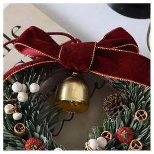 Macro detail of Christmas wreath with velvet bow, golden bells and pine needles
