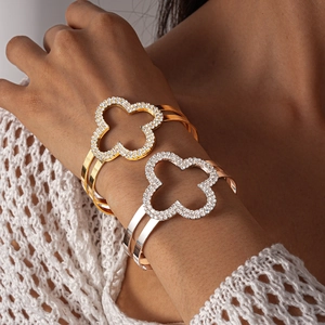 Dettaglio di bracciali rigidi a doppio strato con motivi a quadrifoglio e diamanti