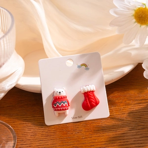 Macro shot of 925 silver polar bear and red Christmas stocking mismatched stud earrings
