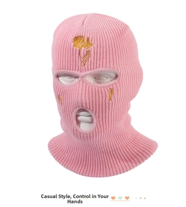 Detail of pink knitted ski mask with gold rose embroidery and lightning bolt symbols