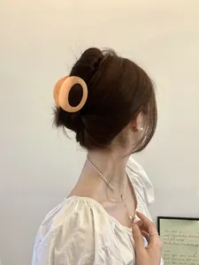 Detail of apricot oval hair claw clip securing a hair bun on model for daily styling