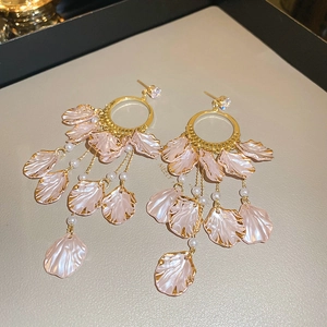 Macro view of long gold tassel earrings with pink shell petals and white pearls