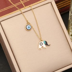 Gold stainless steel evil eye and elephant pendant necklace in a beige jewelry box
