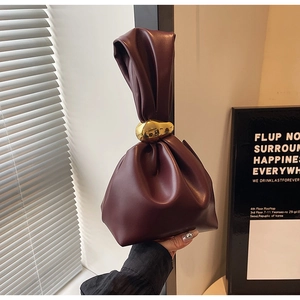 Detail of dark red drawstring bucket bag featuring a unique gold metal ring accent